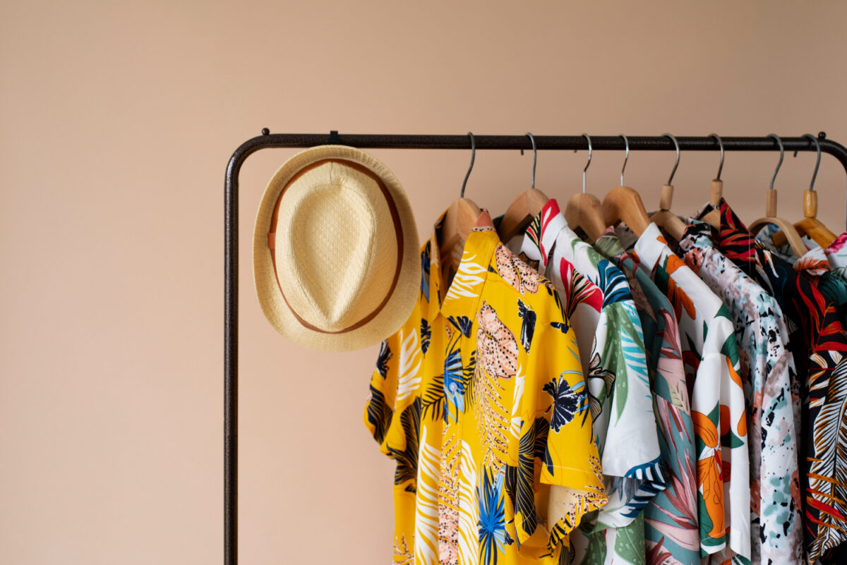 clothing rack with floral hawaiian shirts on hangers and hat